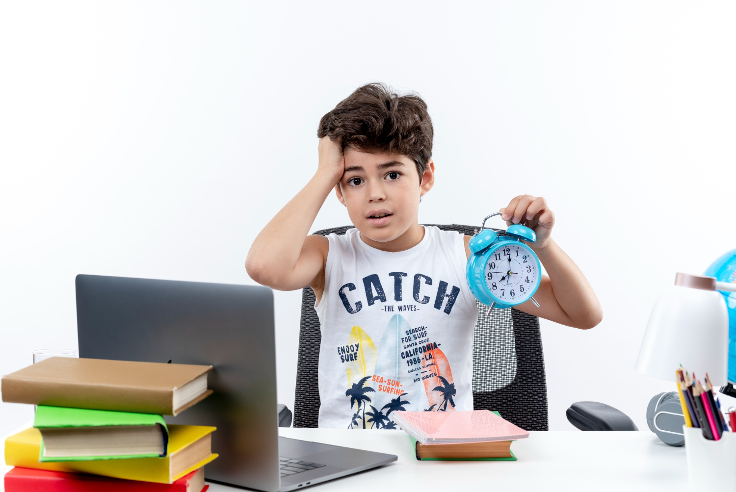 concerned-little-schoolboy-sitting-desk-with-school-tools-holding-alarm-clock-grabbed-head-isolated-white-background